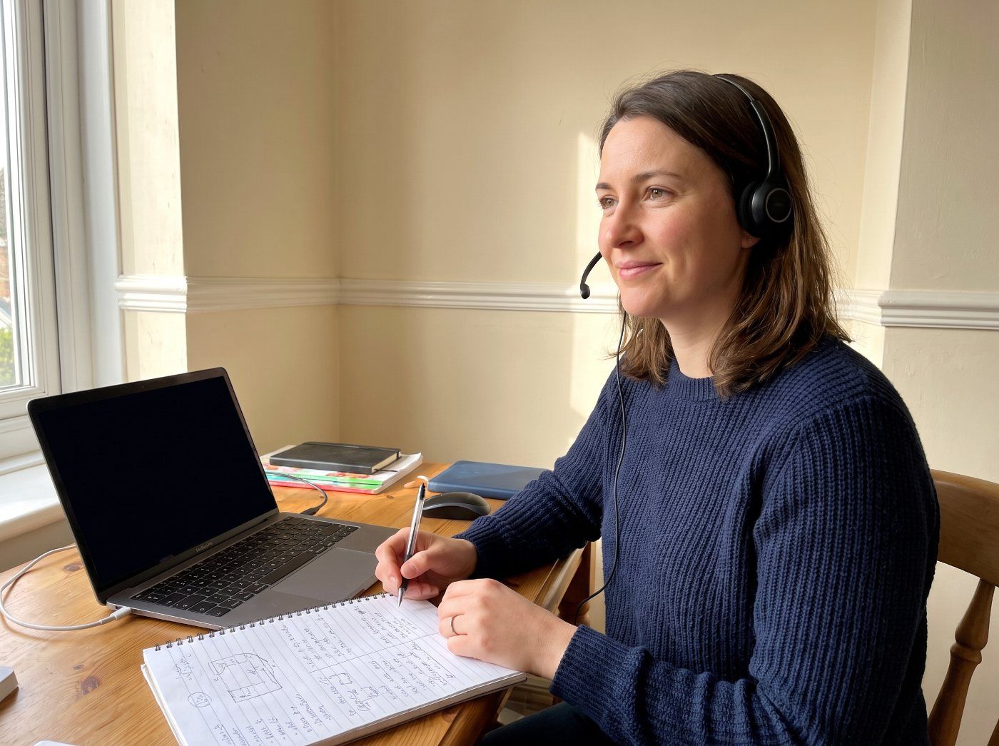 An advisor wearing a headset, taking notes during a client call